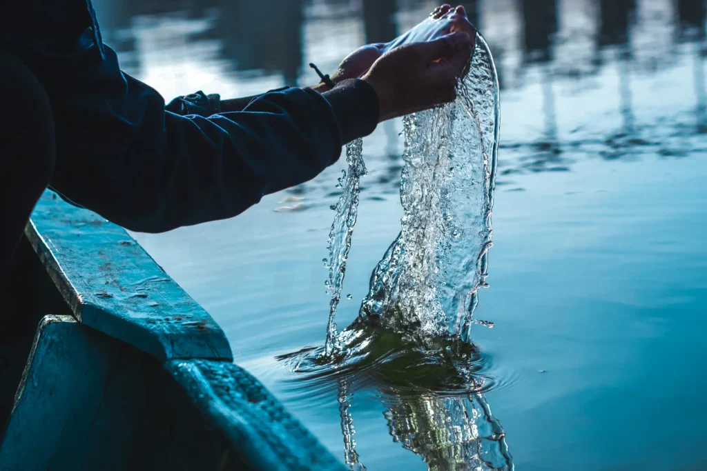 manos recogiendo agua de un lago